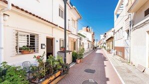 A narrow street lined with traditional buildings, featuring potted plants and outdoor seating. - Sunset House (Málaga)