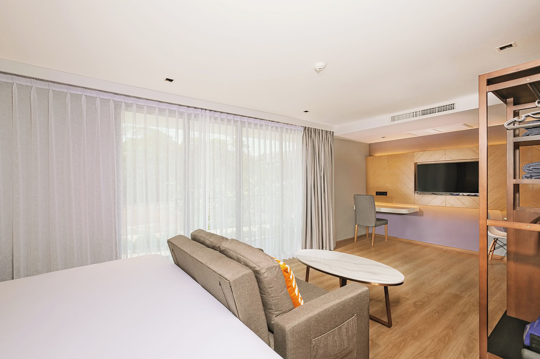 Ett modernt hotellrum med en soffa, ett litet bord, en TV och ett skrivbord.