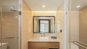 Une salle de bain moderne avec une douche à parois de verre, un meuble-lavabo et un miroir au-dessus du meuble-lavabo.