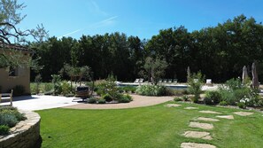 A well-maintained garden with a swimming pool, stone pathway, and outdoor seating. - Contemporary country house with a pool and air conditioning – Luberon. (Roussillon)