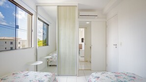 Un dormitorio con dos camas, una ventana y una puerta corredera que da al baño.