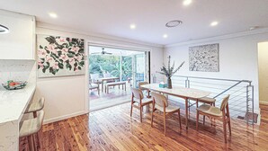 A modern kitchen with wooden flooring, a dining area with a table and chairs, and a view through the glass door to the outside. - ☆☆☆☆☆ Spacious 4-bedrooms apartment in West Ryde (West Ryde)