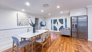 A modern kitchen with a marble countertop, wooden chairs, a grey sofa, and a stainless steel refrigerator. - ☆☆☆☆☆ Spacious 4-bedrooms apartment in West Ryde (West Ryde)