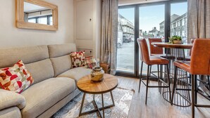 A modern living room with a sofa, coffee table, and dining area with chairs. - 2 bedroom accommodation in Narbeth (Narbeth)