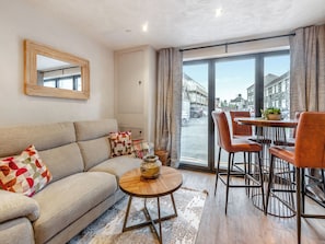 A modern living room with a sofa, coffee table, and dining area with chairs. - 2 bedroom accommodation in Narbeth (Narbeth)