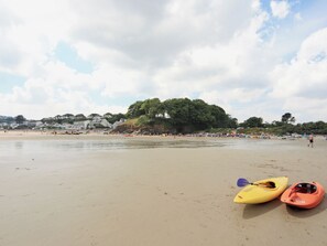 Une plage avec des kayaks et, en arrière-plan, une colline boisée.