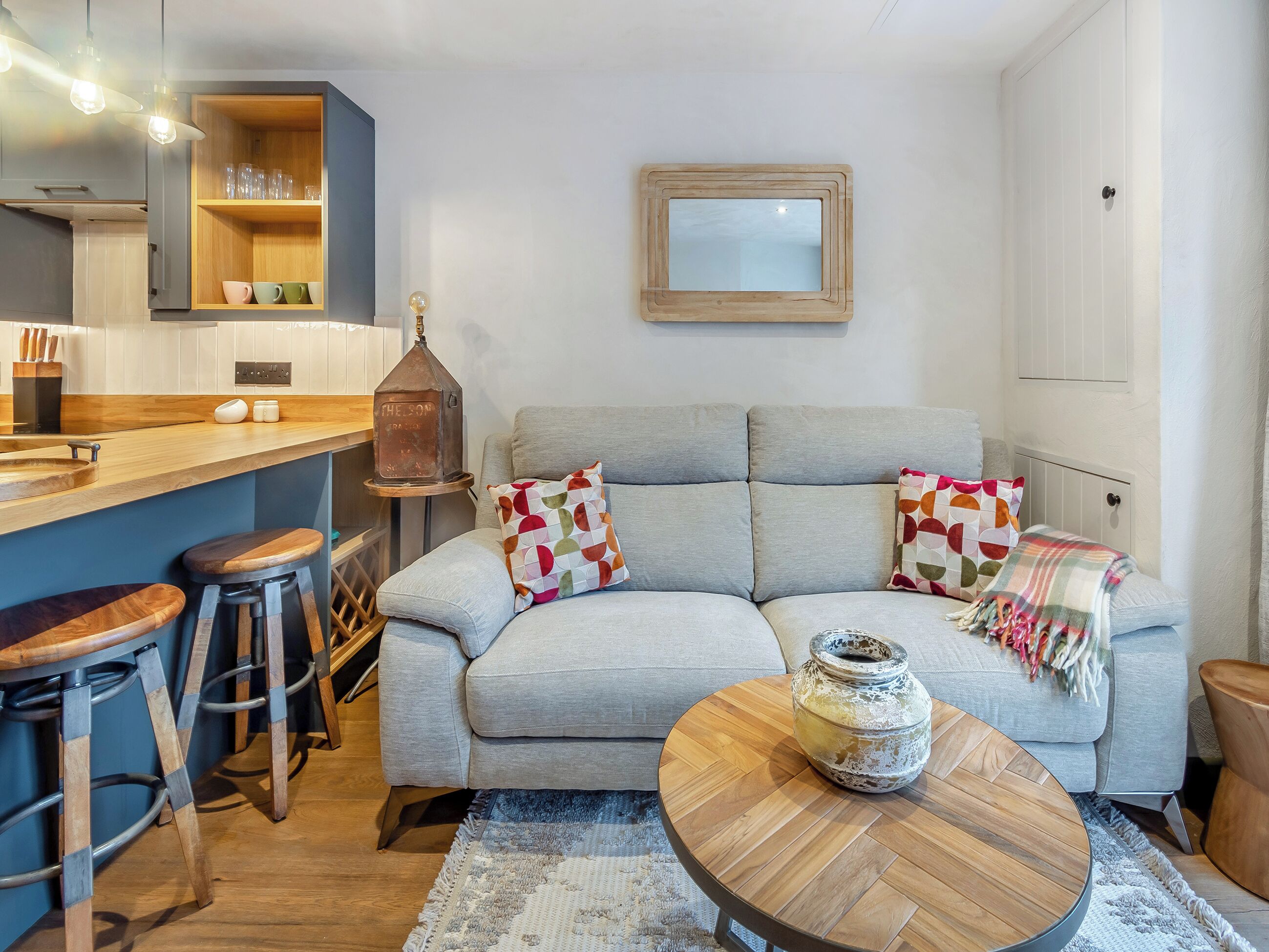 A modern living room with a sofa, a coffee table, and a kitchen area with stools.