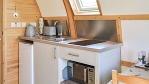 A compact kitchen with a built-in microwave, a kettle, and a sink.
