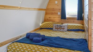 A cozy, wooden-paneled room with a bed featuring patterned bedding and a pillow with the text "Better Together".