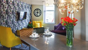 Un salon moderne comprenant un coin repas, un canapé, un téléviseur et un luminaire décoratif.