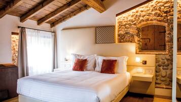Un dormitorio con una cama grande, vigas de madera en el techo, pared de piedra y chimenea de piedra.
