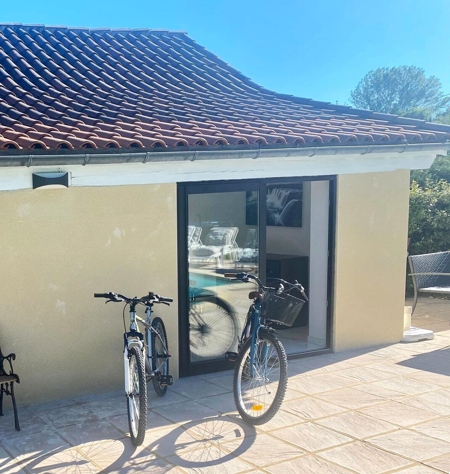 En bygning med et tagtækket tag og en glasdør. To cykler er parkeret udenfor.
