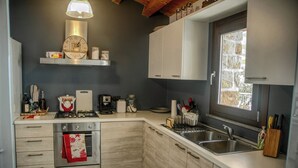 A modern kitchen with light wood cabinets, a built-in oven, a gas stove, and a window providing natural light.