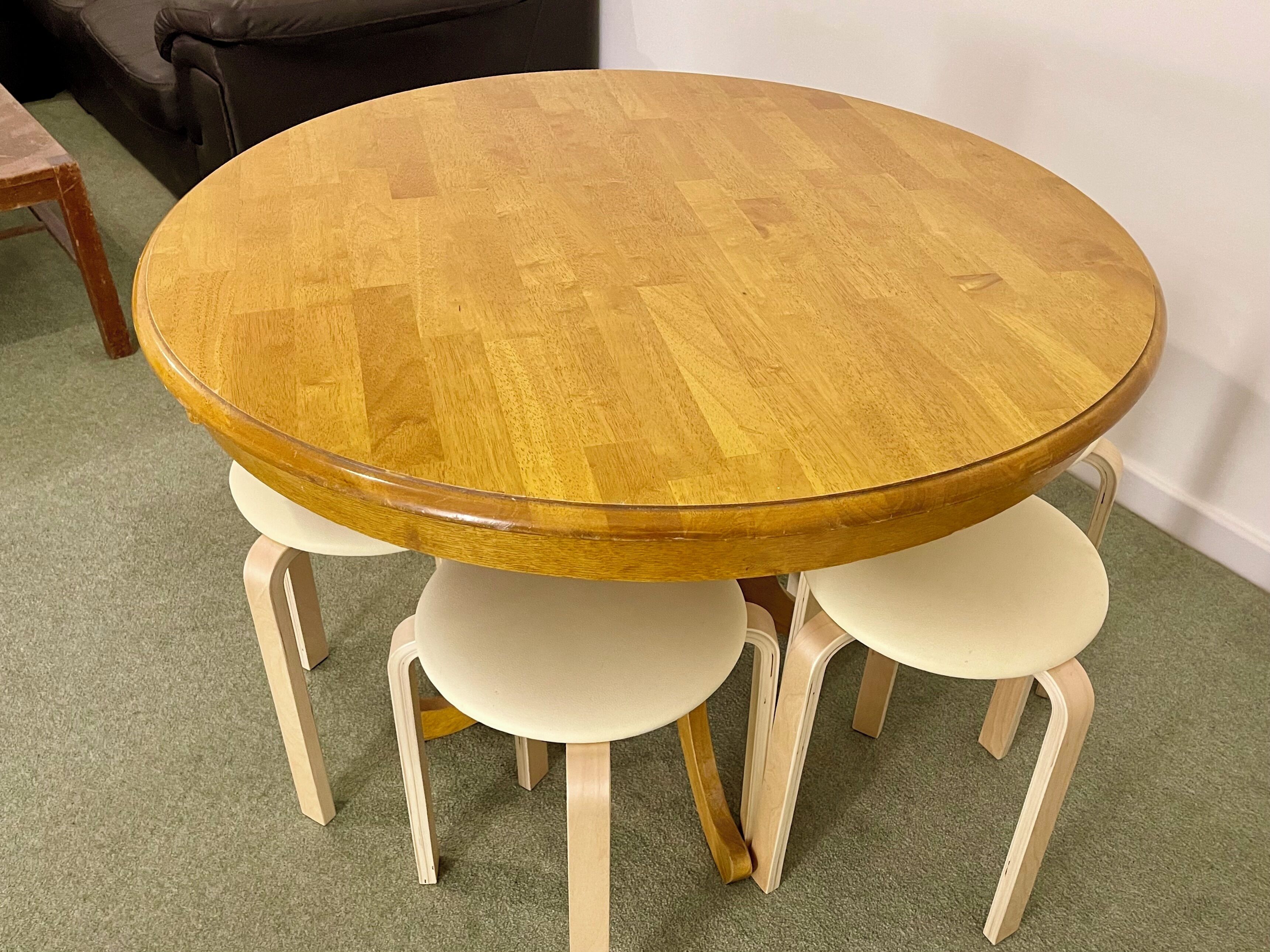 Una mesa redonda de madera con cuatro sillas blancas.