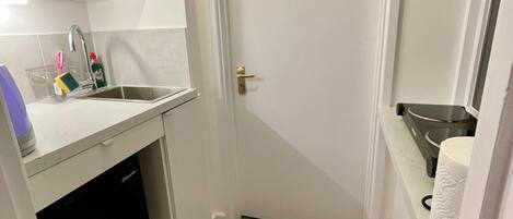 Eine kleine Küche mit integriertem Mikrowellenherd, einer Spüle und einer Arbeitsplatte.