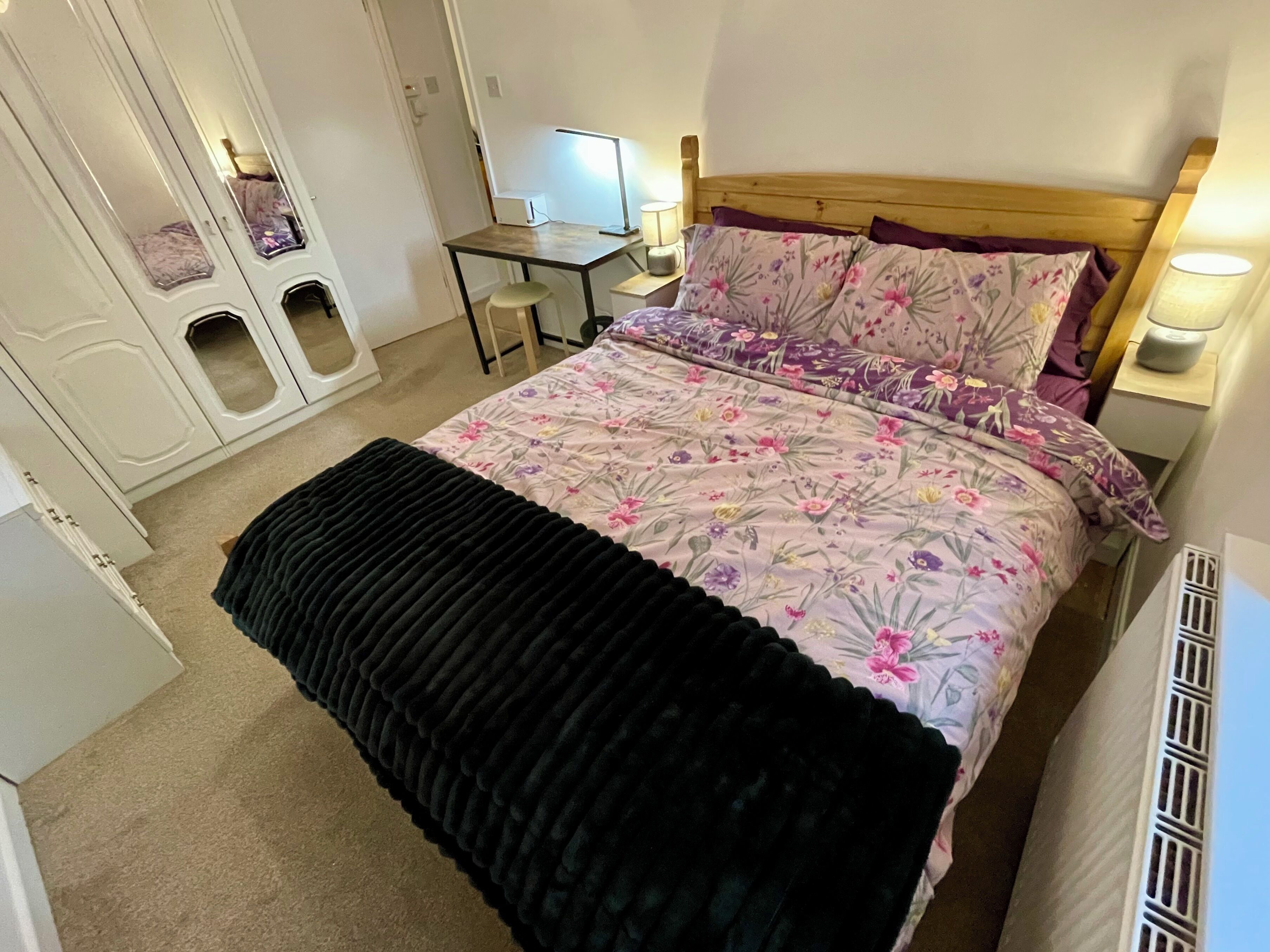A bedroom with a bed, a desk, and a computer.