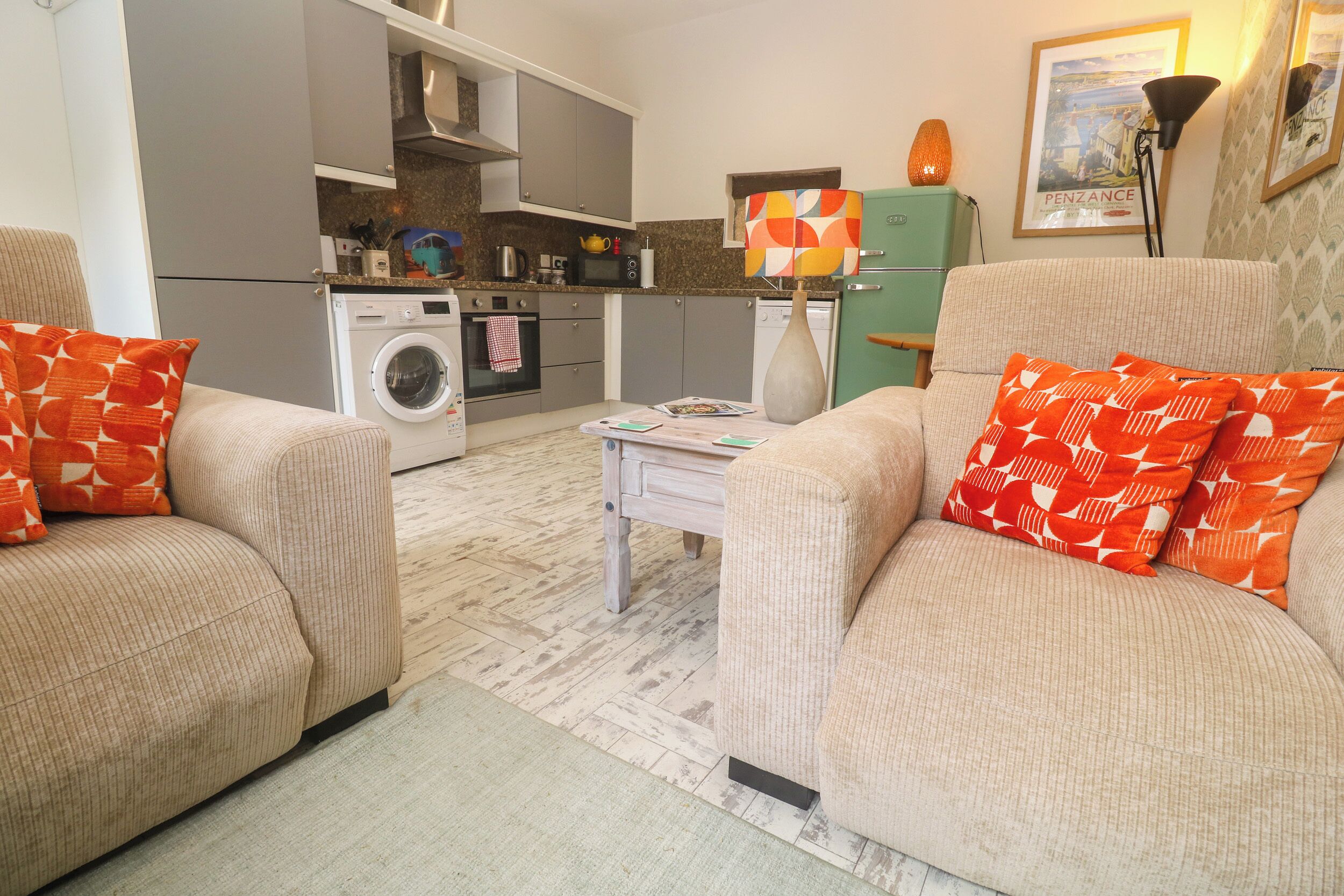 Un espacio habitable funcional con sofá, lavadora y zona de comedor.