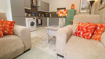Un espacio habitable funcional con sofá, lavadora y zona de comedor.