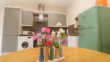 Una cocina con una mesa de madera, un refrigerador verde y una lavadora.
