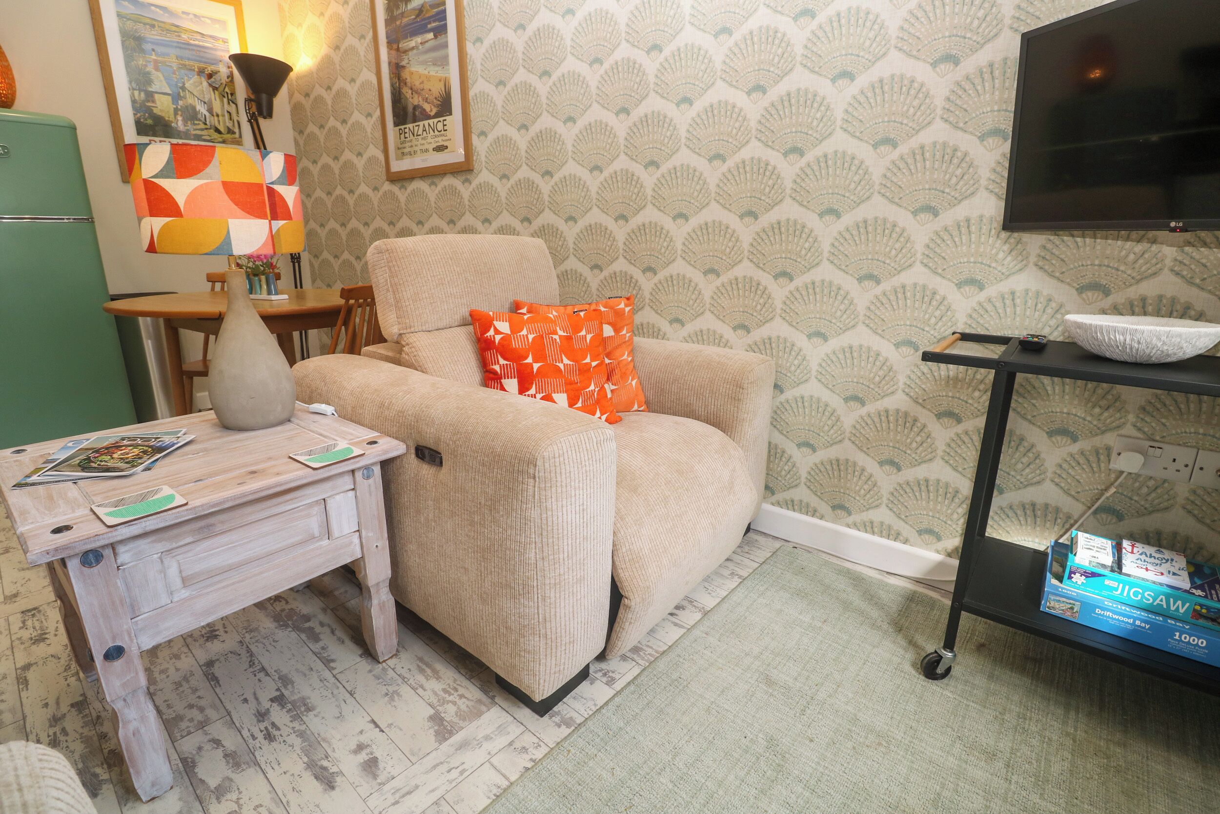 Un salón con sofá, mesa de centro, mueble para televisión y papel tapiz estampado.