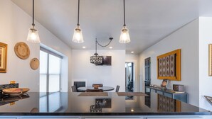 A modern kitchen with a central island, white cabinetry, and pendant lighting.