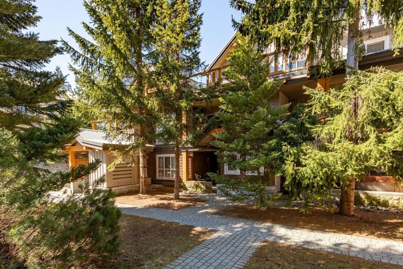 A lodge with a wooden exterior, a covered outdoor seating area, and a paved walkway.