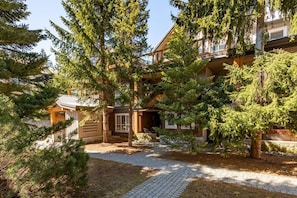 Un chalet avec une façade en bois, un espace extérieur couvert avec des sièges et un chemin pavé.