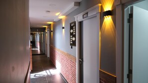 A hotel corridor with a brick accent wall, directional signs, and a door labeled 205. - Amed Sur Hotel (Diyarbakir)