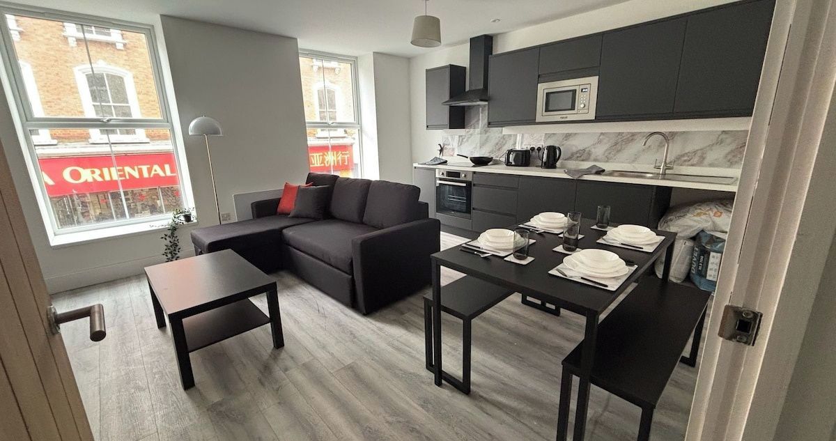 Un espai de vida modern amb sofà, taula de dinar i zona de cuina.