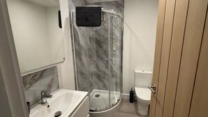 Uma casa de banho moderna com chuveiro em cabine de vidro, lavatório branco e sanita.