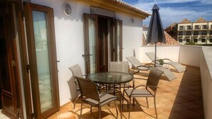 An outdoor patio with a round table and chairs, a glass door, and a tiled floor. - Loft located in the city center with a large terrace and good sun exposure (Tavira)