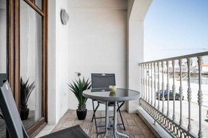 A balcony with a round table, two potted plants, and a chair.