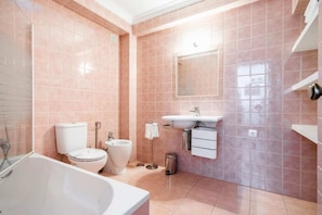 A bathroom with a bathtub, toilet, bidet, and sink.