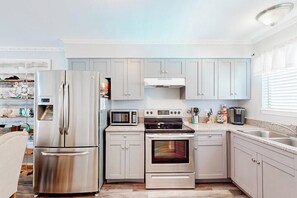 A modern kitchen with stainless steel appliances, light-colored cabinetry, and a granite countertop.