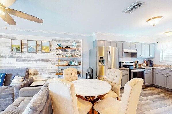 A modern kitchen with a built-in oven, a refrigerator, and a dining area with a round table and chairs.