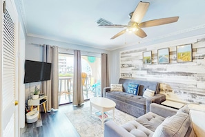 Un salon moderne doté d’un ventilateur de plafond, d’un téléviseur à écran plat, d’un canapé et d’une table basse.