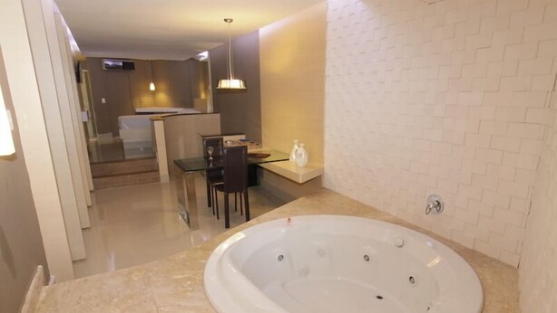 Ein modernes Badezimmer mit einer großen Badewanne, einer Duschkabine aus Glas und einem Essbereich mit Tisch und Stühlen.