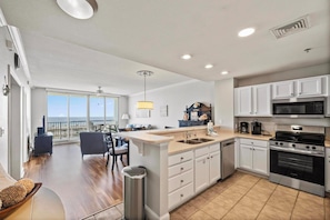 Enjoy cooking in this well-equipped kitchen with a microwave, oven, and sink, and dine in the adjacent dining area with a table and chairs.