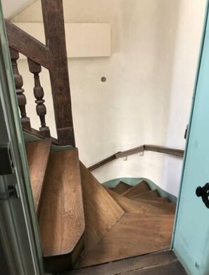 A wooden staircase with a handrail and a light blue door at the bottom.