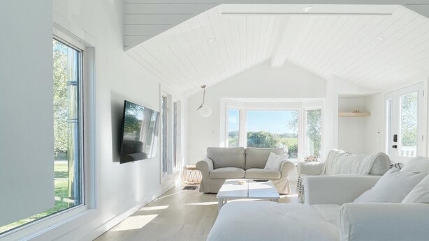 Un soggiorno spazioso con soffitto alto, ampie finestre e colori bianchi moderni.