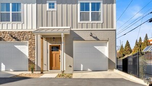 Un edificio residenziale a due piani con facciata in pietra, due porte per garage e un piccolo portico.