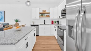 A modern kitchen with white cabinets, a granite countertop, stainless steel appliances, and wooden flooring. - Gated Community~Brand new townhouse~Downtown Rome (Rome)