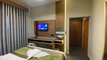 Ein Hotelzimmer mit Bett, Schreibtisch, Fernseher, Spiegel und Kleiderschrank.