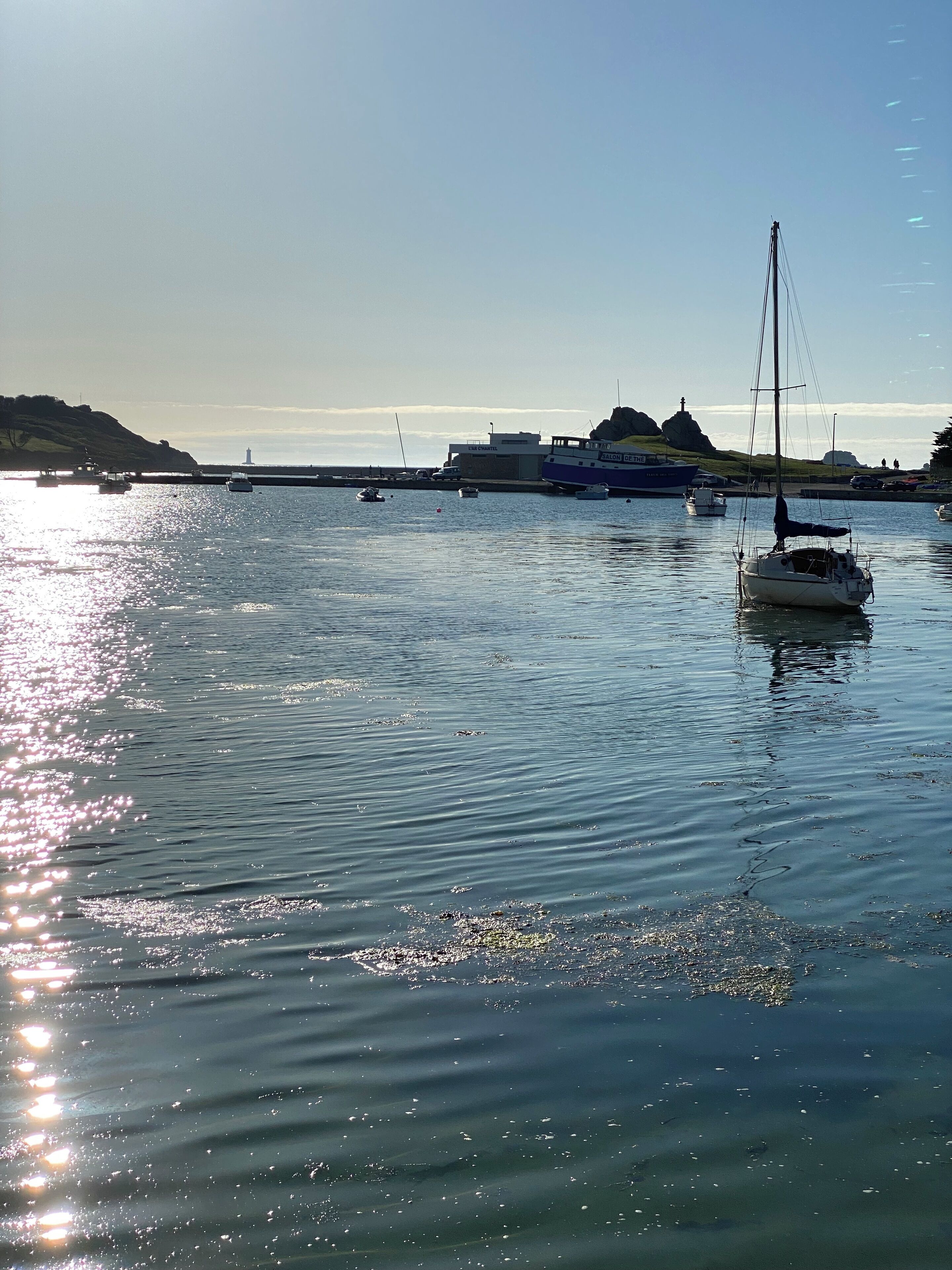 A harbor with boats, a lighthouse, and a building with signage.