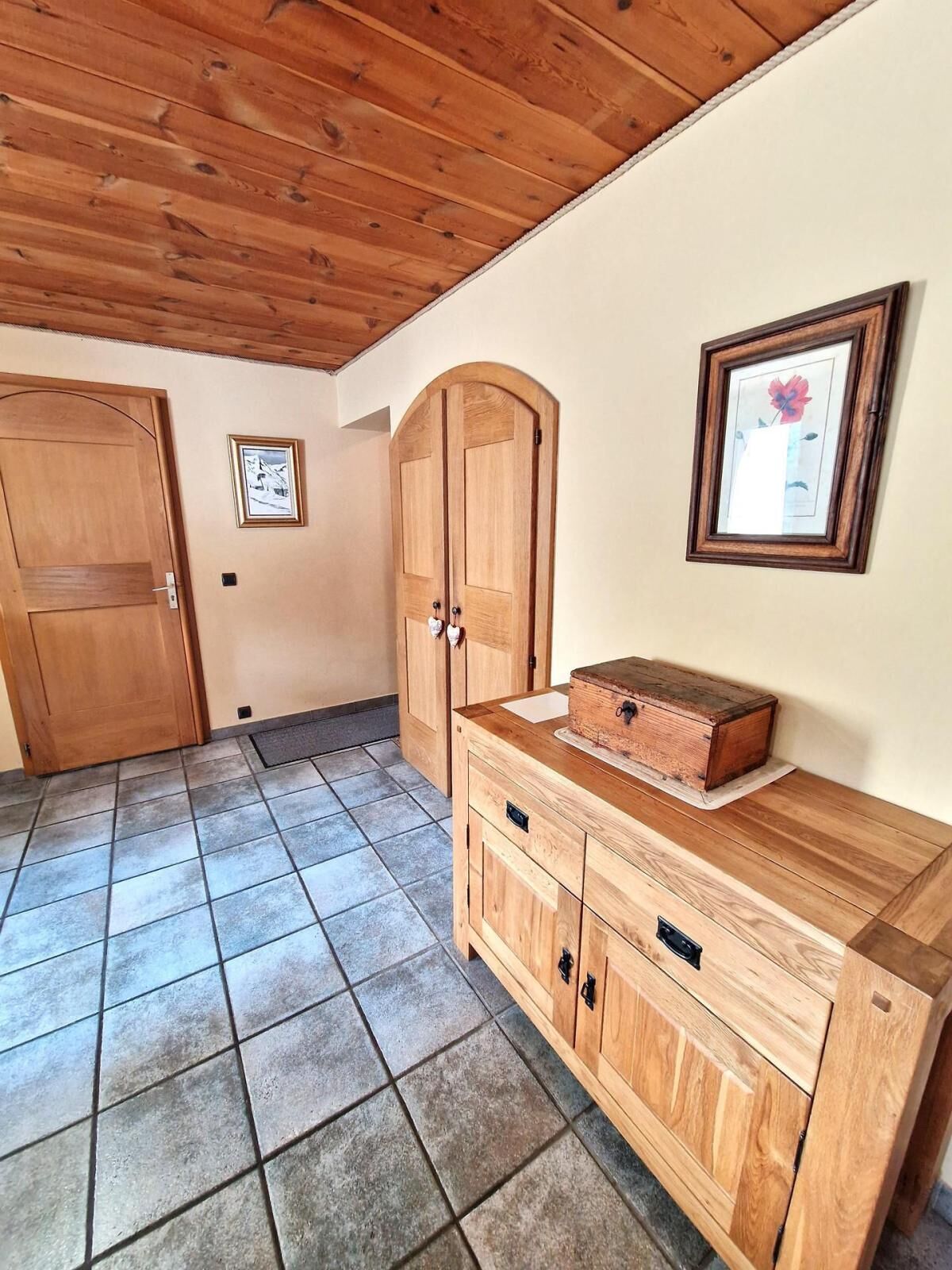 A room with a wooden cabinet, a framed picture, and a tiled floor.