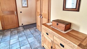Ein Zimmer mit einem Holzschrank, einem gerahmten Bild und einem Fliesenboden.