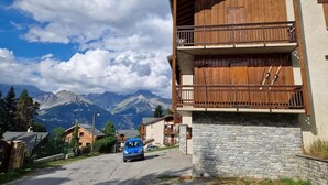 Ein Holzhaus mit Steinfundament, einem Balkon und Blick auf die Berge.