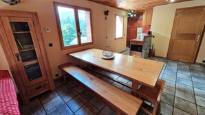 Eine gemütliche Küche mit Holztisch und Bänken, einem Fenster mit Blick und einer Tür, die nach draußen führt.