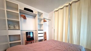 A bedroom with a large bed, built-in shelving, a television, and a wardrobe. - 20m from ski slopes, Ground floor, view ski slopes, balcony, tv, ski locker, 32m², Valfréjus (Valfréjus)