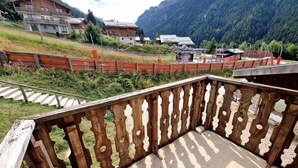 A wooden balcony with a view of a mountainous landscape, a wooden fence, and a paved area. - 20m from ski slopes, Ground floor, view ski slopes, balcony, tv, ski locker, 32m², Valfréjus (Valfréjus)